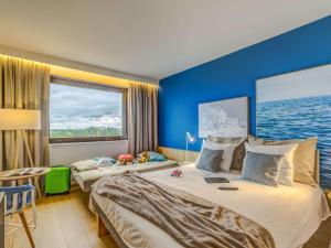 a bedroom with two beds and a large window at Novotel Gdańsk Marina in Gdańsk