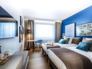 a hotel room with two beds and a table at Novotel Gdańsk Marina in Gdańsk