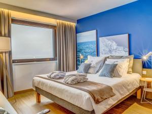 a bedroom with a large bed with a blue wall at Novotel Gdańsk Marina in Gdańsk