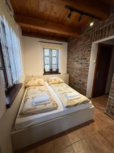 GraboszyceにあるDomek Bomba Zator Graboszyceのレンガの壁のある部屋にある大きなベッド +5枚の写真