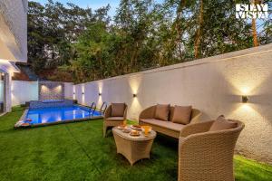 un patio con sillas y una mesa junto a la piscina en StayVista at Casa Elyra with Pool, AC, Balcony, en Lonavala