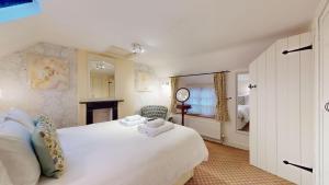 ein Schlafzimmer mit einem großen weißen Bett und einem Stuhl in der Unterkunft Hannah Cottage in Adderbury