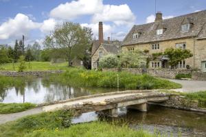a stone bridge over a river in a village at Claytons Cottage in Adlestrop