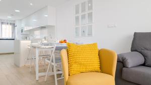 ein Wohnzimmer mit einem gelben Stuhl und einer Küche in der Unterkunft PANORAMIC relax apartment in Finestrat