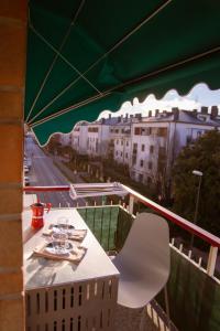a table and a white chair on a balcony at Es Apartament in Treviso