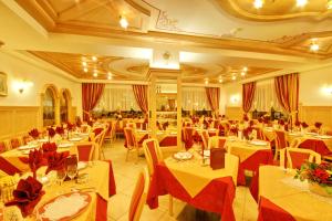 un comedor con mesas y sillas con manteles rojos en Hotel Villa Cima Undici, en Pozza di Fassa
