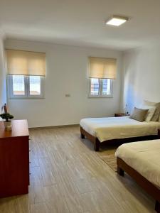 a room with two beds and a table and two windows at Gomes Equestre in Golegã