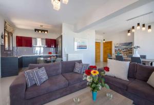 a living room with a brown couch and a kitchen at Marilia by Vintage Travel in Maleme