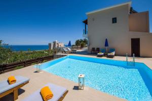 a swimming pool in front of a house with the ocean at Marilia by Vintage Travel in Maleme