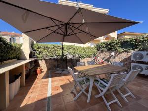 a wooden table with chairs and an umbrella on a patio at Villa Sole e Luna - Key to Villas in Valledoria