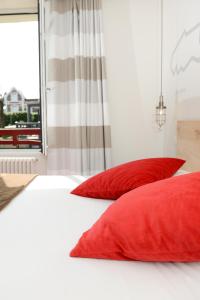 two red pillows on a white bed with a window at Hôtel Ar Iniz in Saint Malo