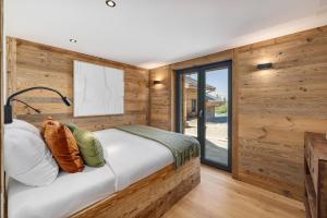 una camera da letto con pareti in legno e un letto con cuscini di Chalet Le Reve Cinema room Jacuzzi a Riddes