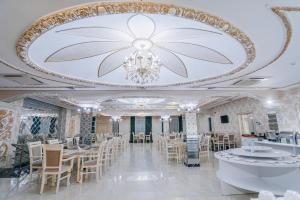Un comedor con una lámpara de araña y mesas y sillas. en GRAND HOTEL SOGDIANA, en Samarkand