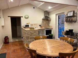 a kitchen with a wooden table and chairs in a room at Le Mas du Pigeonnier in Réauville