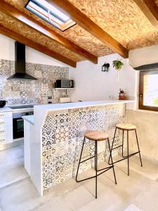 a kitchen with a counter and two stools at Ca Turón casa de pueblo in Planes +10 photos