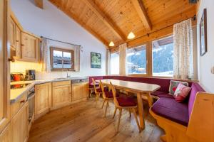 une cuisine avec une table et un canapé pourpre dans l'établissement Schöneben Chalet Wiesenwald, à Wald im Pinzgau