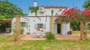 ein weißes Haus mit einem Tisch im Hof in der Unterkunft Huerta Valleciruelo Sanlúcar La Mayor by Ruralidays in Sanlúcar la Mayor