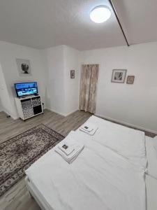 a bedroom with a bed with white sheets and a tv at Quartier Wenzelnberg in Langenfeld