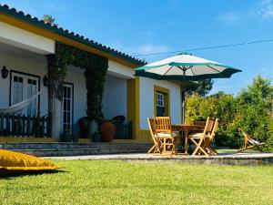 a house with a table and chairs and an umbrella at Casa de Santiago in São Tiago de Besteiros