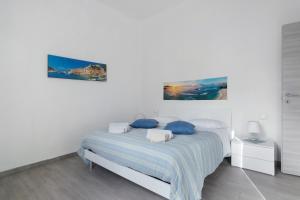 Un dormitorio blanco con una cama con almohadas azules. en Georgehouse Golfo dei Poeti 5 Terre, en La Spezia