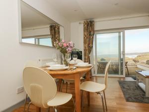 ein Esszimmer mit einem Tisch und Stühlen mit Aussicht in der Unterkunft Catch the Wave in Newquay