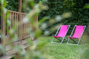 two pink chairs sitting in the grass near a fence at Camping Seasonova Le Plan d'Eau in Saint-Yrieix-sur-Charente