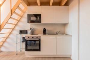 eine Küche mit weißen Schränken und einem Herd in der Unterkunft Studio pour deux en mezzanine avec petit balcon in Villeneuve d'Ascq