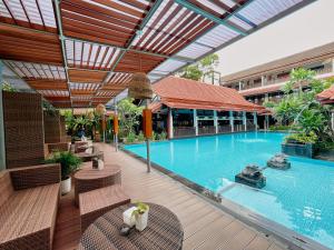 a large swimming pool with chairs and a building at Paku Mas Hotel in Yogyakarta