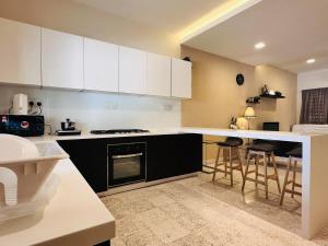 eine Küche mit weißen Schränken und einer Theke mit Barhockern in der Unterkunft New Island Luxe Retreat Vacation Home 14pax Nearby Gurney in Tanjung Bungah