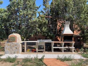 a house with a fireplace and a building with trees at Casa Rural Villamur in Guadamur