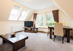 a living room with a table and a television at Claymore Apartments in Pitlochry
