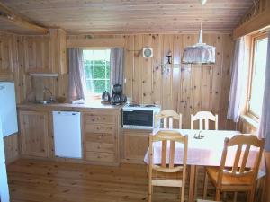 a kitchen with wooden walls and a table with chairs at Haugland Gard in Haugaland