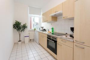 a kitchen with wooden cabinets and a potted tree in it at Macabu Apartment Zoe in Chemnitz
