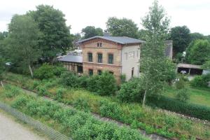 an old brick building with trees and bushes at Ferienwohnung Stationsgebäude in Wallsbüll +15 photos