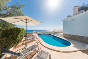 a swimming pool with chairs and an umbrella at San Jaime View - stunning sea views close to resort in Son Bou