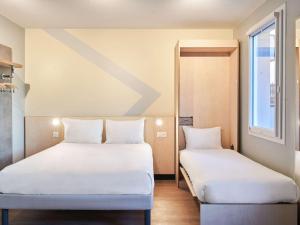 two beds with white sheets in a room at ibis budget Issy Les Moulineaux Paris Ouest in Issy-les-Moulineaux