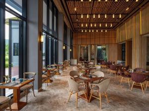 a restaurant with tables and chairs and windows at dusitD2 Khao Yai in Mu Si