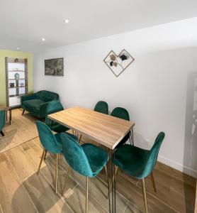 a dining room with a table and green chairs at Maison 3 chambres 6 pers RER A, L Paris direct in Maisons-Laffitte