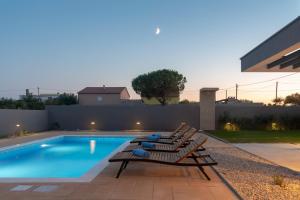 a swimming pool with two lounge chairs next to it at Beautiful Villa Aria in Zadar