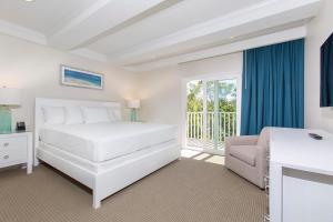 a white bedroom with a bed and a balcony at The Fold Hotels Indian Shores in Clearwater Beach