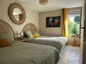 a bedroom with two beds and a mirror and a window at La grangette in Marseillan +31 photos