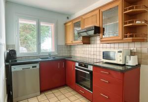 a kitchen with red cabinets and a microwave at La Casablanca - Guyancourt in Guyancourt +16 photos