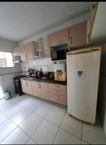 eine Küche mit weißem Kühlschrank und Holzschränken in der Unterkunft COP 30 Suíte Confortável com Varanda in Belém