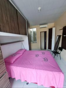ein Schlafzimmer mit einem rosa Bett mit einer rosa Decke in der Unterkunft COP 30 Suíte Confortável com Varanda in Belém