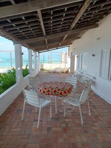 einen Tisch und Stühle auf einer Terrasse mit Meerblick in der Unterkunft Occa Búzios in Nísia Floresta