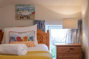 a bedroom with a bed and a lamp and a window at Smiddy Burn Cottage Kingsbarns in Kingsbarns