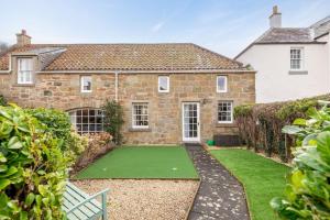 an exterior view of a house with a putting green at Smiddy Burn Cottage Kingsbarns in Kingsbarns +22 photos