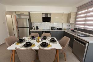 a kitchen with a white table and chairs in a kitchen at Jasmine Gray by HolidayKeys in Kyrenia