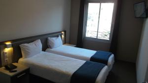 um quarto de hotel com duas camas e uma janela em Appart'hotel le Pèlerin em Lourdes