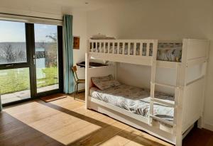 ペンブルックシャーにあるGreenshutters PembrokeshireBeachHouseの二段ベッド2台と窓のある寝室